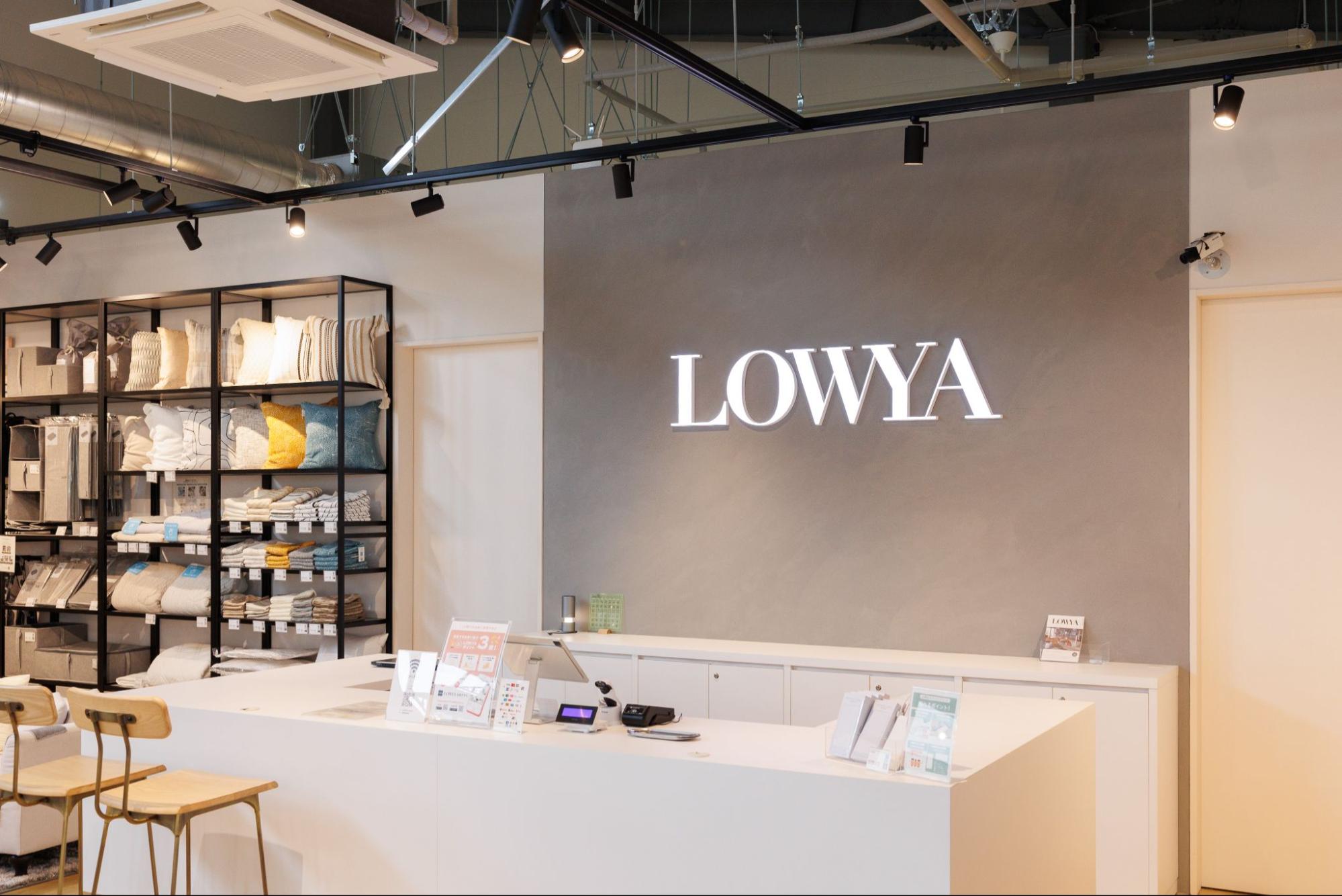 LOWYA店舗内のカウンターと壁に設置されたロゴ。左手には棚に陳列された商品が見える。