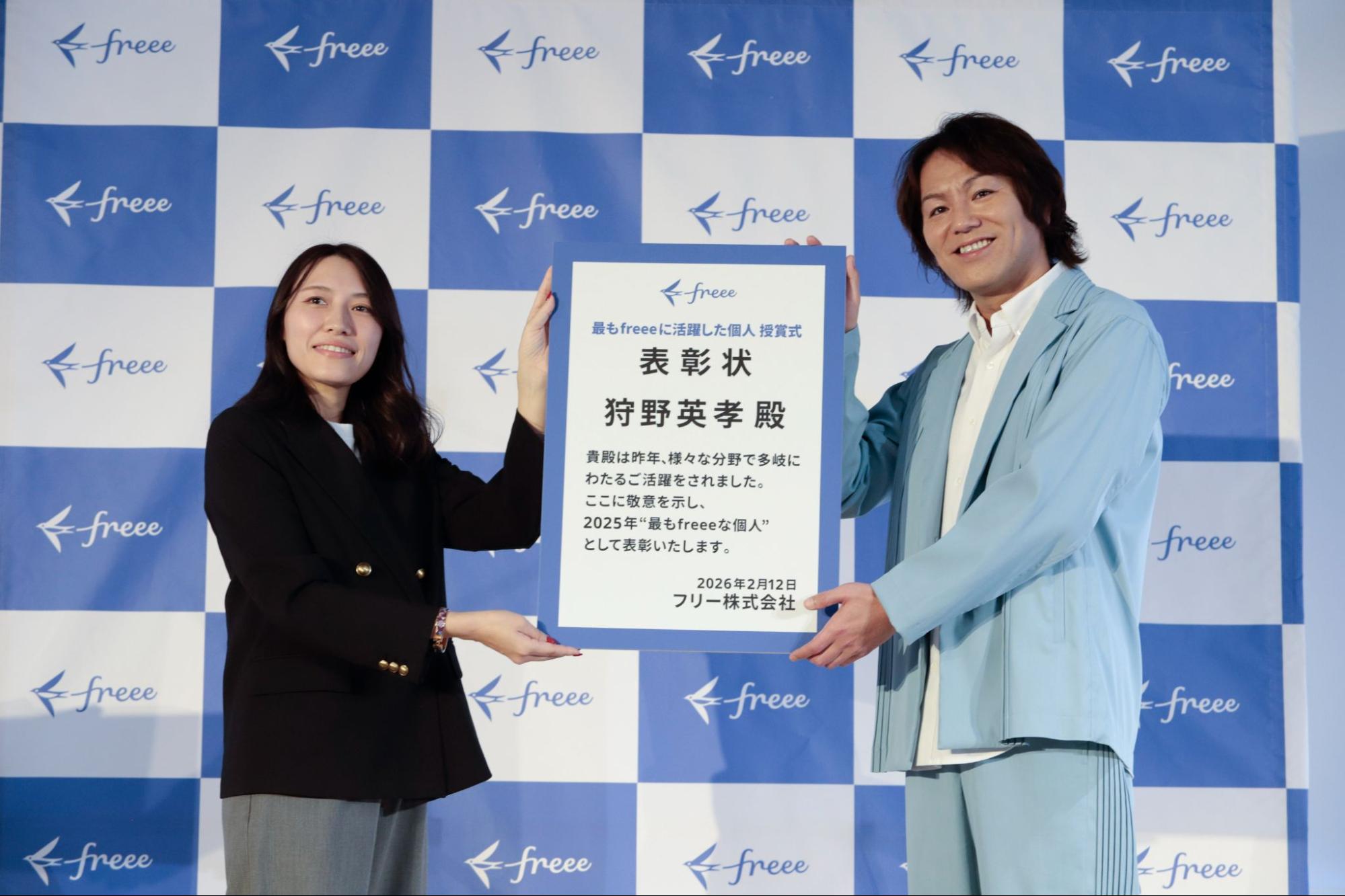 パネルを持つ、左freeeの社員と狩野英孝 氏