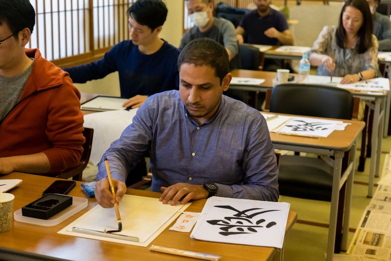 A focused non-Japanese guest using his brush to create beautiful strokes