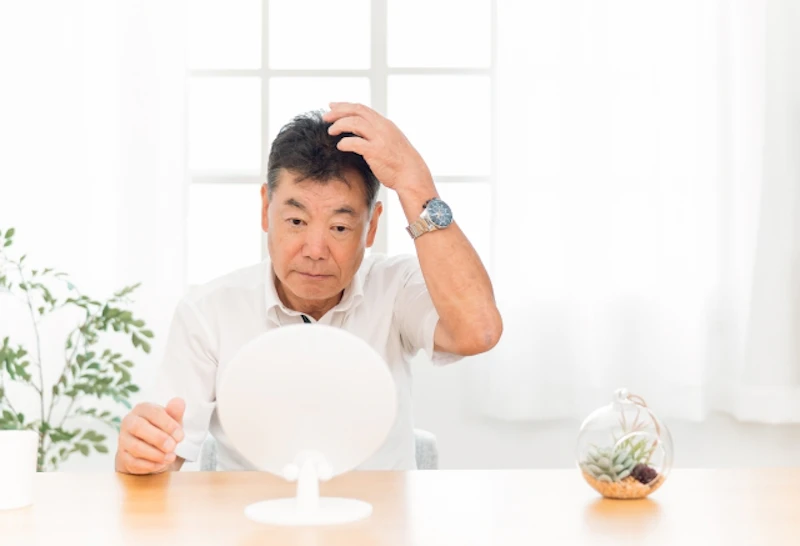 出かける前に髪を整える中高年男性