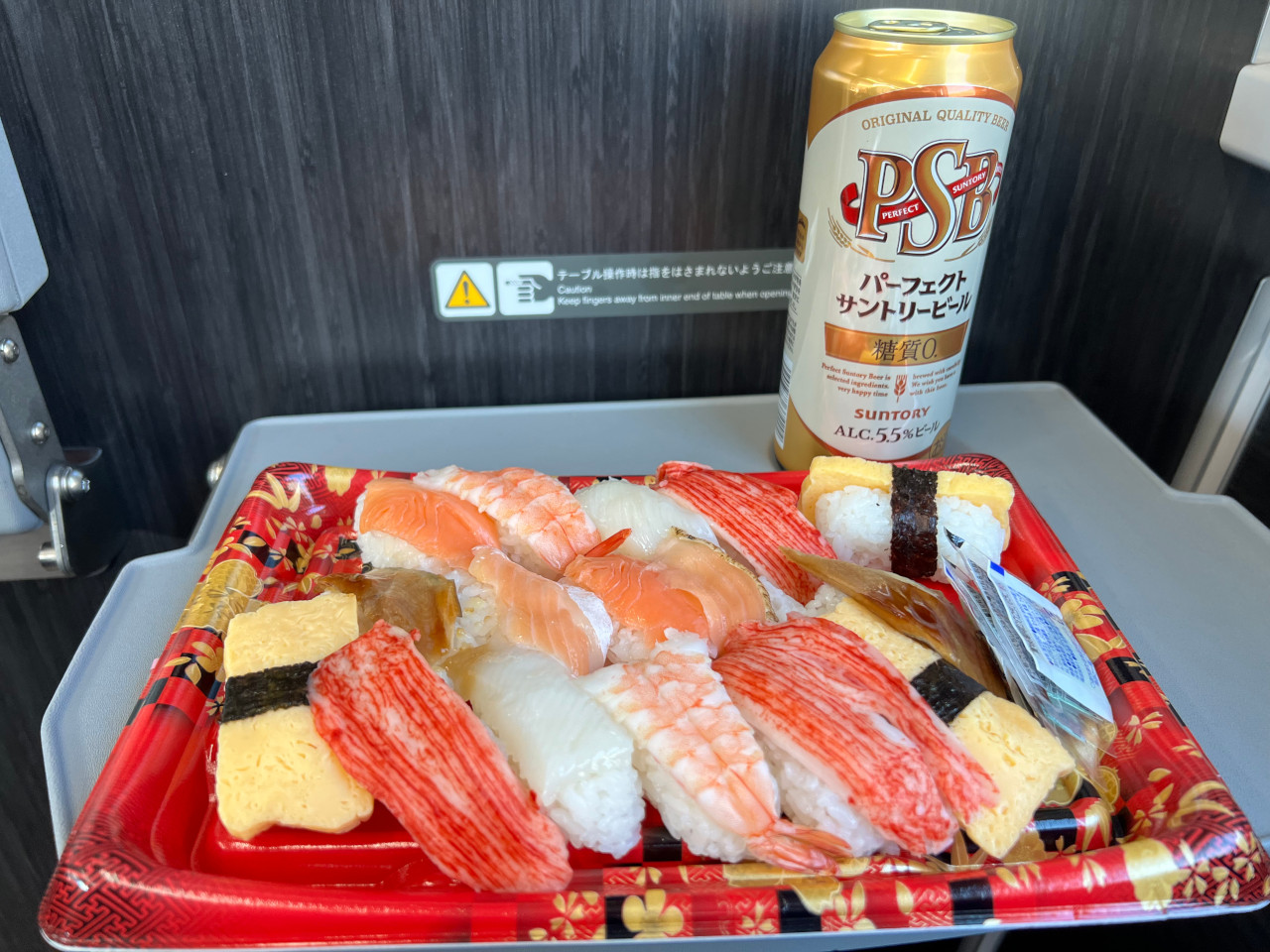 グリーン席のテーブルに寿司と缶ビールが置いてある画像