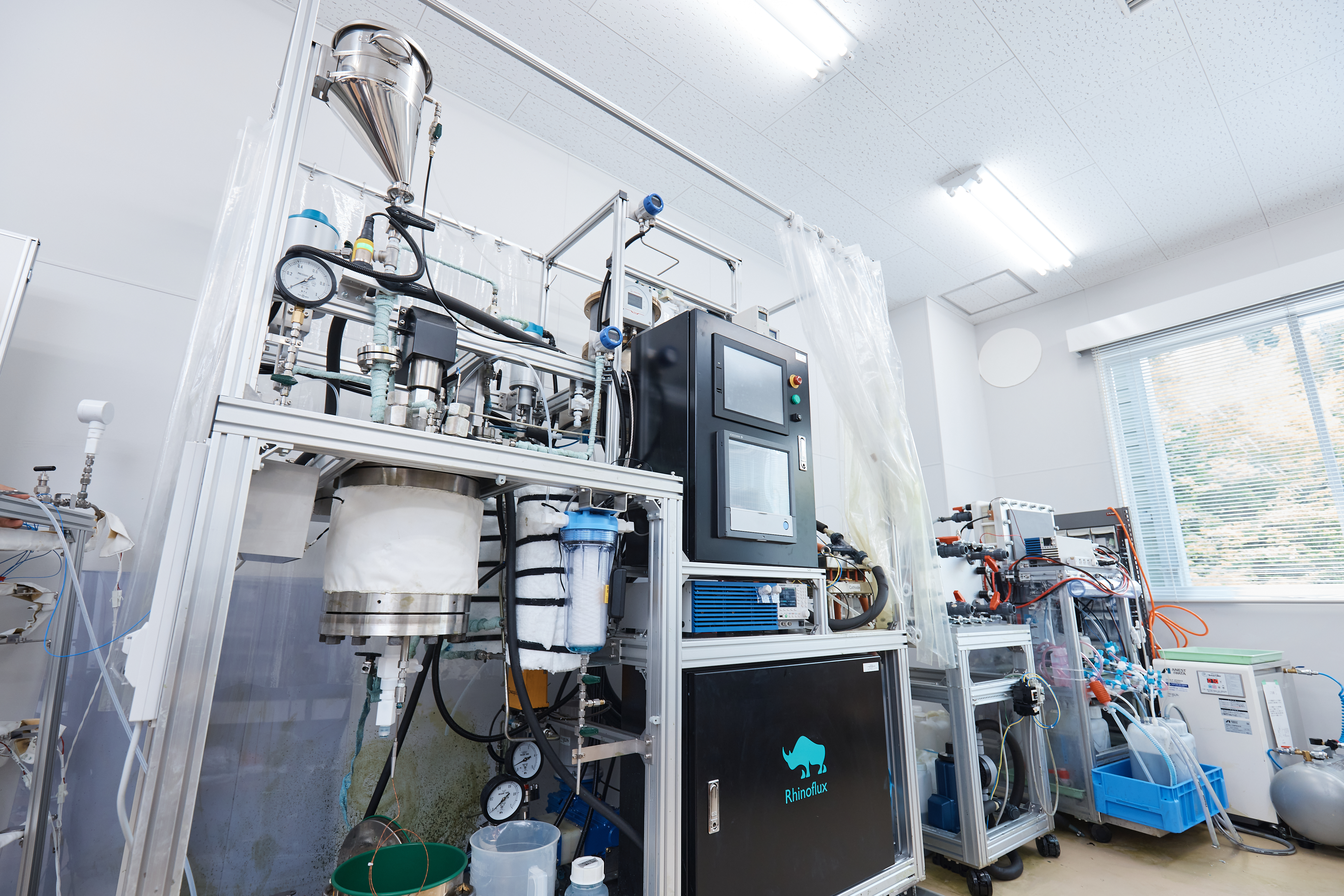 ライノフラックスは、2025年開発の小型実証機「Katsura-1J」に、飲料工場などで発生した残渣を投入し、実証を行っている。サイズは１畳ほど。