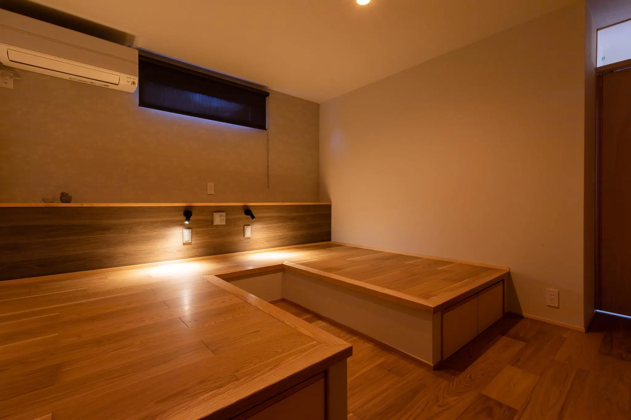 小林創建によるリノベーション後の寝室。布団を敷くための収納付き木製小上がりを造作し、ヘッドボードに間接照明を設置。窓を小さくし、落ち着いた雰囲気に仕上げた和モダンな空間。