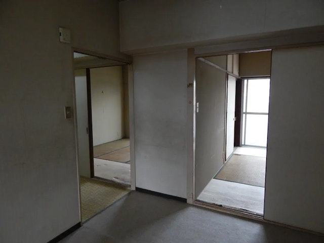 リノベーション前のマンション室内の写真。壁で細かく仕切られており、部屋の中心にあるため光が届かず薄暗い。床の一部には古い畳が見える。