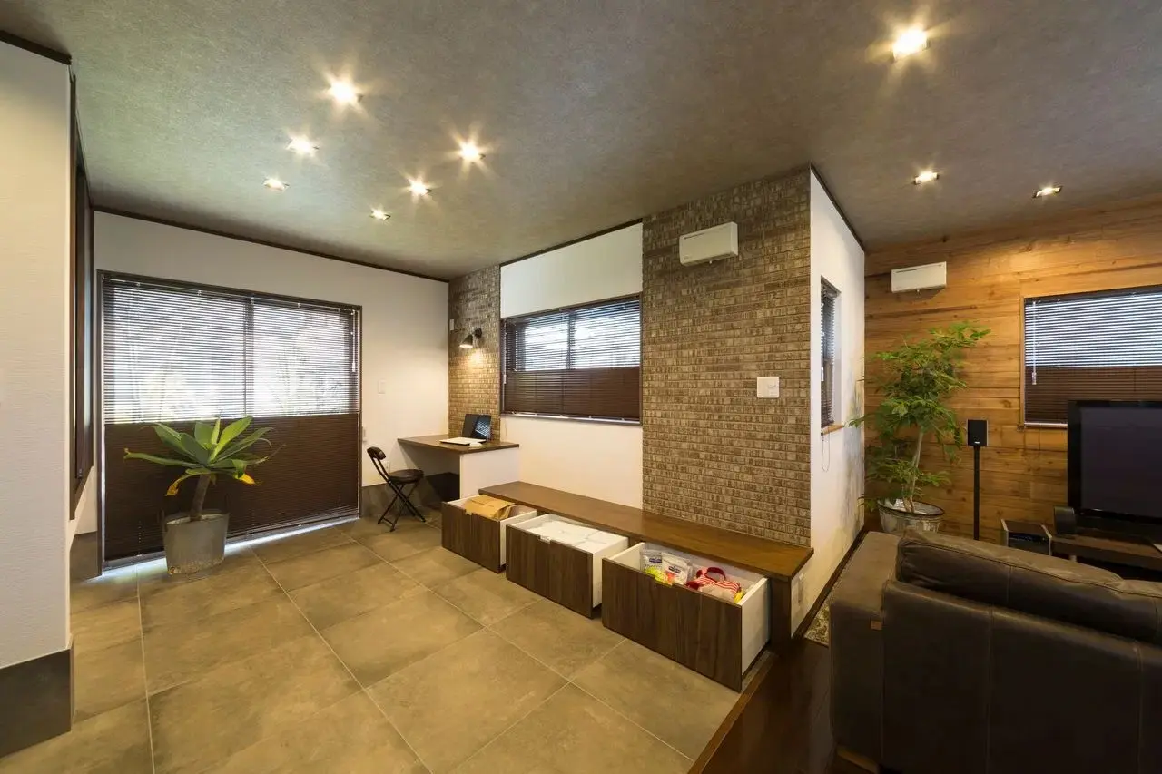 手入れしやすいタイル床の多目的スペースと、テレビ背面の足場板アクセントウォールが特徴的なLDK。元和室を愛犬の遊び場兼ワークスペースに改装し、収納も造作したペットと暮らす住まい。an cubeの施工事例。