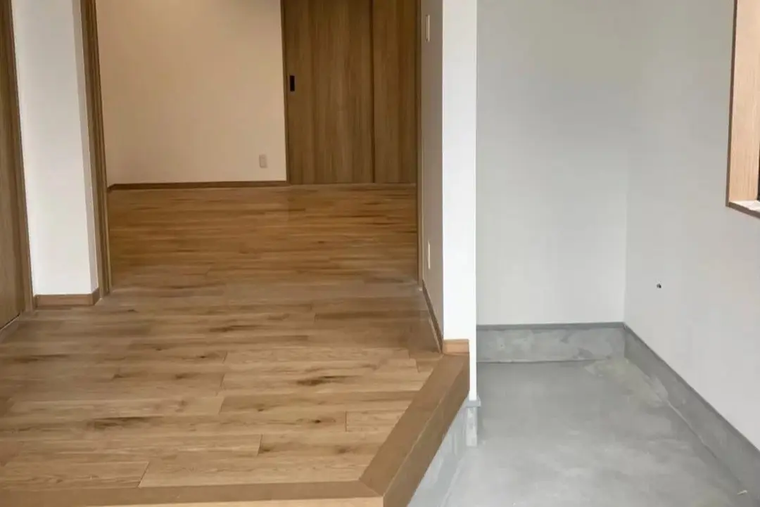 コンクリート土間と木目調フローリングが広がる玄関ホール。奥には同じ木目の引き戸を配置し、ナチュラルでスッキリとした空間となっている。an cube(アン キューブ)のリノベーション事例。