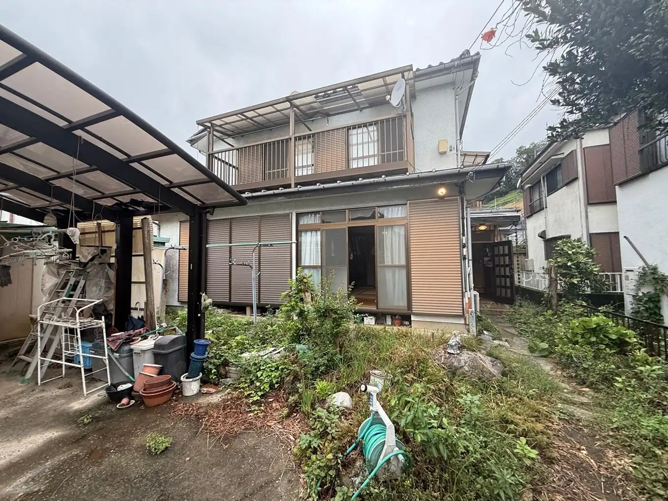 昭和58年築の戸建て外観。リノベ前は古いテラス屋根と庭木が残る相続物件の様子