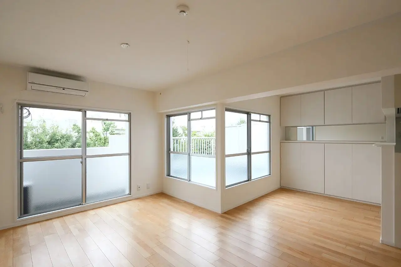 リノベーション後のLDKの写真。床は明るい木目調で、壁2面に窓が設置されている。右手の壁には白い造作収納が取り付けられている。