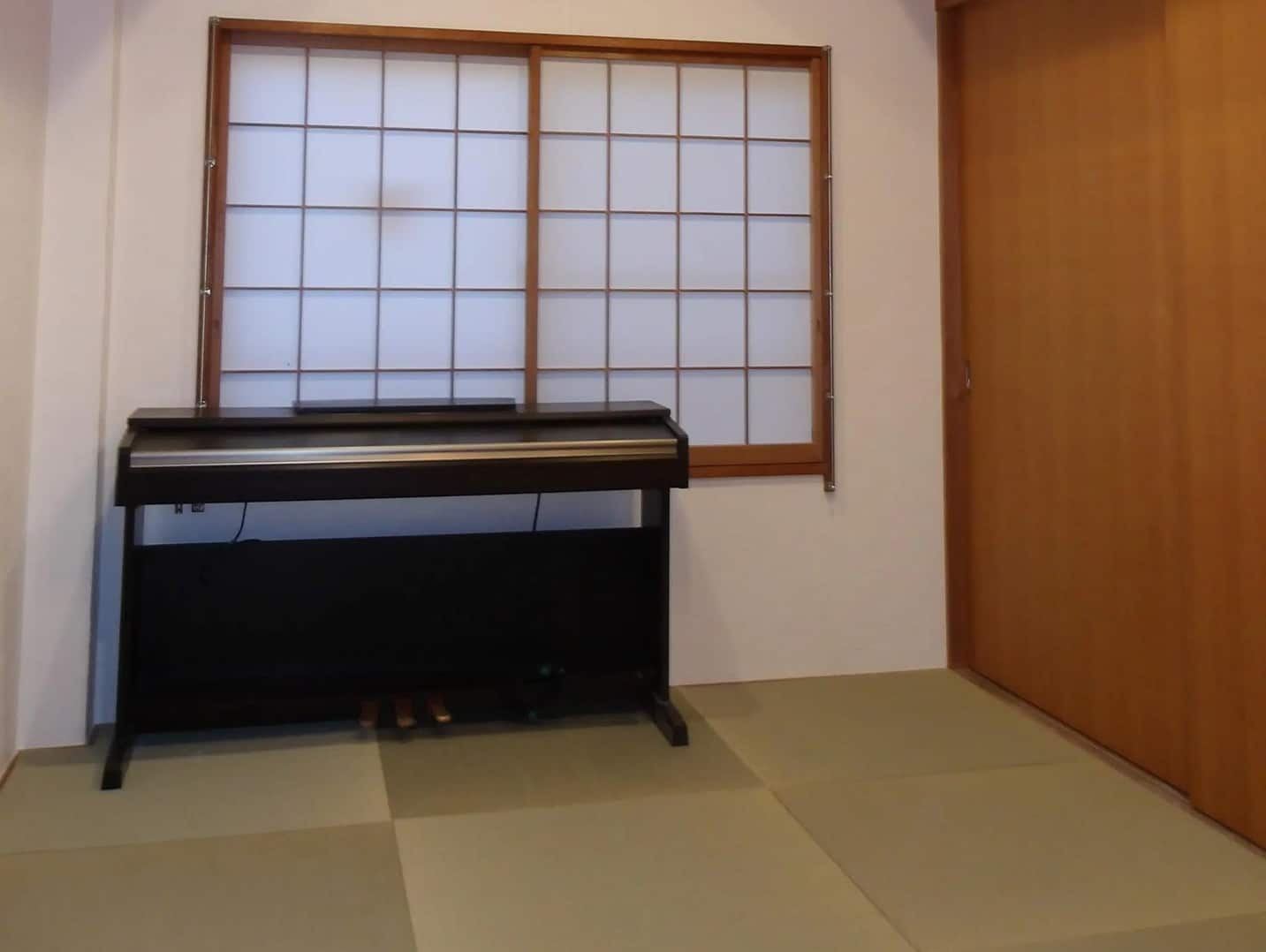 正方形の畳（琉球畳）が敷かれた空間に、木枠の障子窓と電子ピアノが配置されている。壁は無添加漆喰で仕上げられたシンプルで落ち着いた内観。