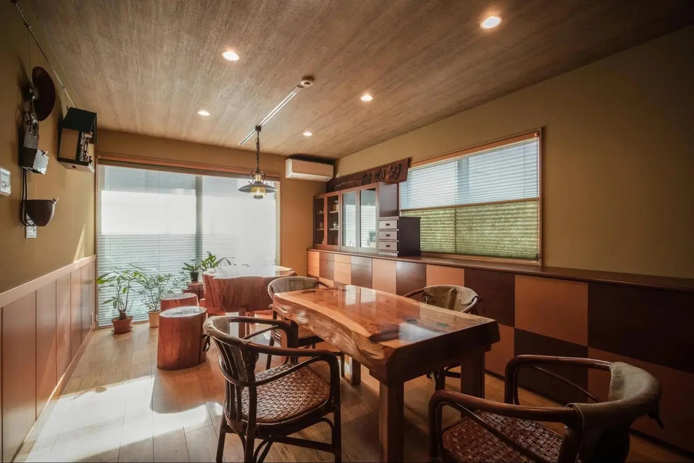 株式会社アイ・シー・ジーのリノベーション事例。一枚板の無垢テーブルとラタンチェアが置かれた和モダンのダイニング。壁面には市松模様の造作収納があり、天井は木目で落ち着いたレトロな雰囲気。