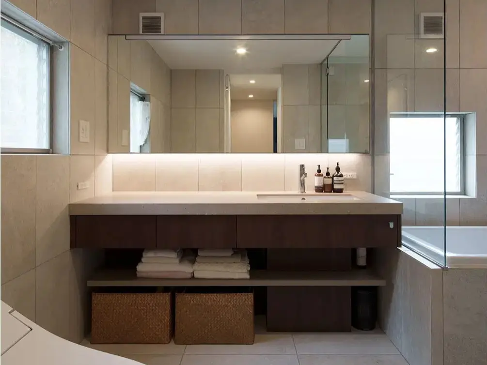 バスルームとの間をガラス扉で仕切り、開放的でホテルのような優雅さを演出したサニタリー空間。見栄えのバランスを第一に考え、質感やデザインにこだわって選ばれたシックな洗面台。メゾネットマンションをフルリノベーションした、インテリックス空間設計の施工事例。