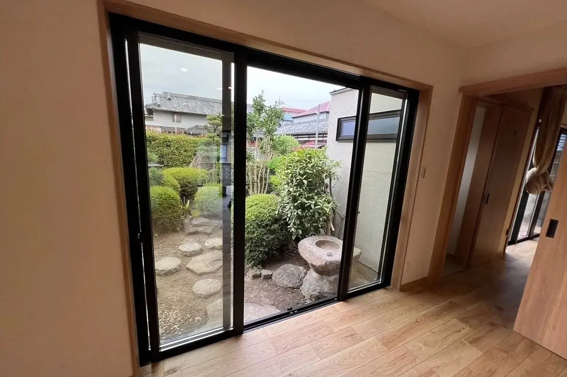 LDKの大きな掃き出し窓から、飛び石や手水鉢が置かれた日本庭園(中庭)が見える。室内の床は明るい木目調。