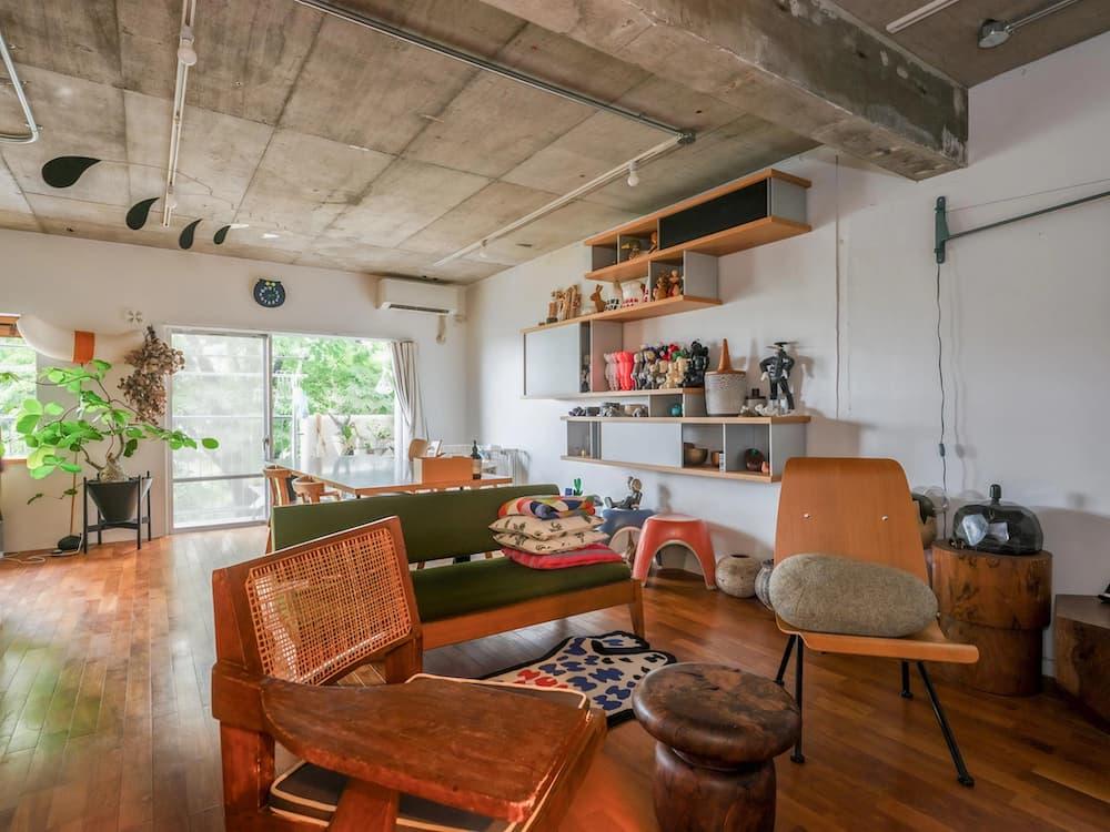 躯体現しのコンクリート天井と木の家具が調和したインダストリアルリノベーションのリビング。壁面収納やグリーンが彩るこだわりの空間事例