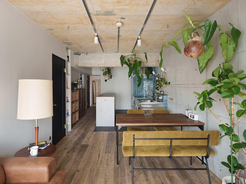 コンクリート現しの壁と天井に観葉植物が映える、グリーン溢れるインダストリアルリノベーション。ステンレスキッチンや古材フローリングを組み合わせたカフェ風のLDK事例