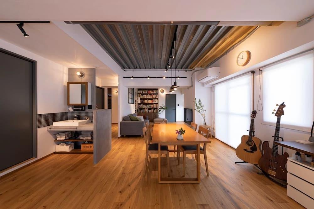 天井現しのデッキプレートと木製フローリングが調和した、楽器と本棚のあインダストリアルリノベーションのLDK