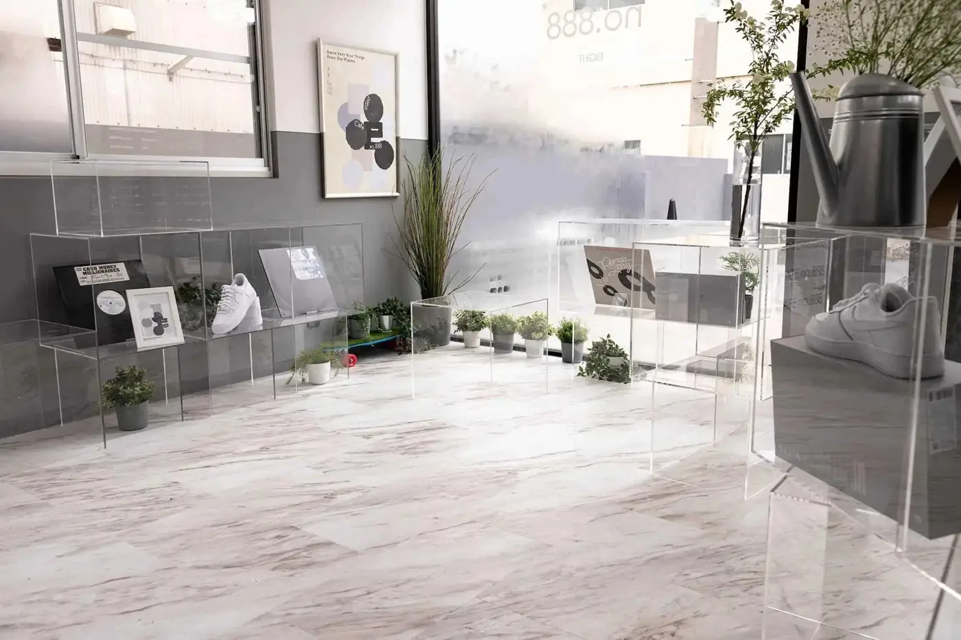 友安製作所のリノベーション事例。コンテナを改装した韓国風カフェの店内。白い大理石調の床とグレーの壁のモノトーン空間に、透明なアクリル什器や観葉植物がスタイリッシュに配置されている。