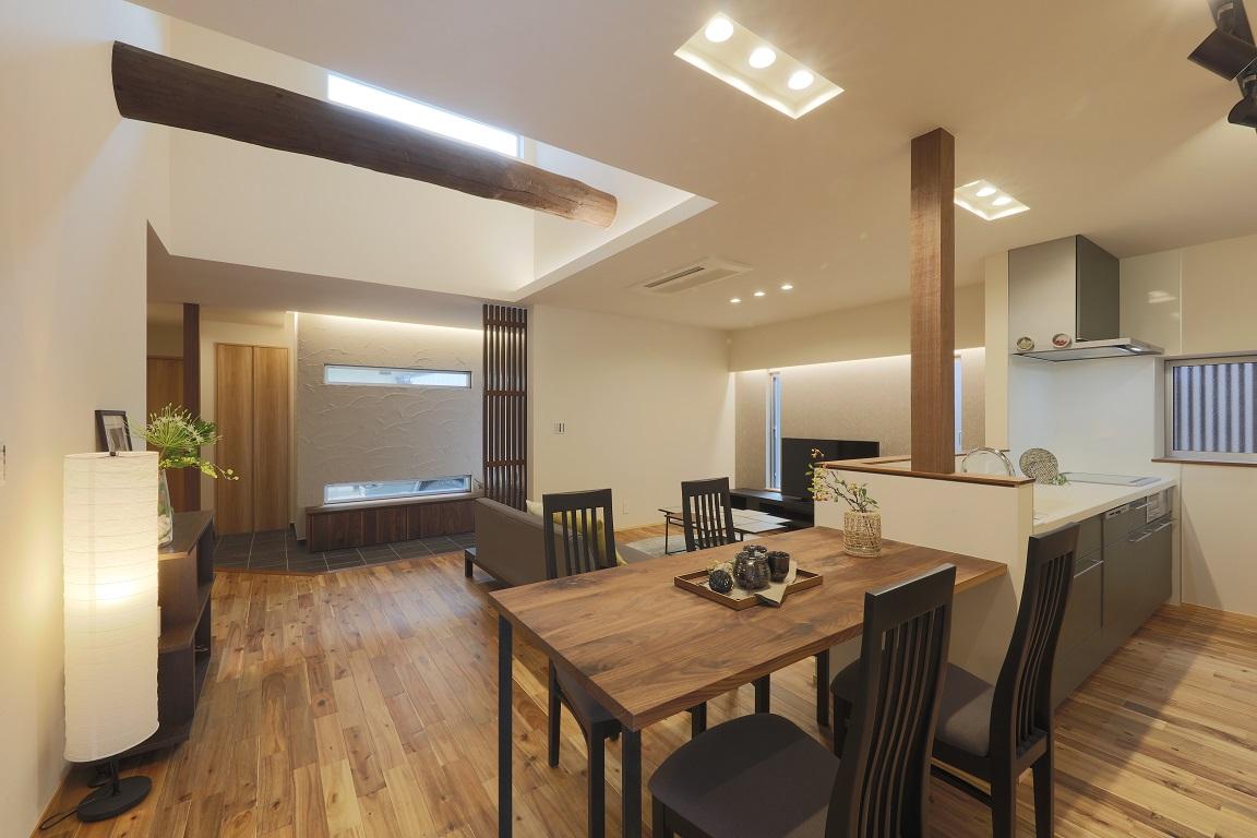 グレーの対面キッチンとダイニング、その奥に広がる土間スペースが一体となったLDK。減築リノベーションによって生まれた勾配天井には既存の梁が現しになり、新旧の素材が調和した開放的な内観。