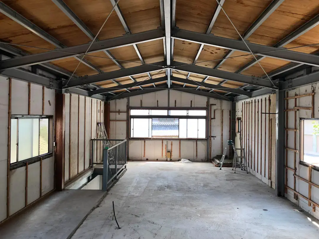 内壁や床、天井材をすべて撤去し、鉄骨の柱や梁、木造の屋根組だけを残したスケルトン状態の倉庫2階。ここからインナーガレージ付きのナチュラルモダンな住居へとフルリノベーションしていく、間取り計画前の様子。株式会社松岡住研｜リノベースの施工事例。