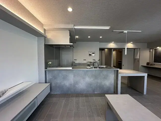 株式会社リノベーション東京の事例。内装からキッチン設備、床材まで徹底してグレーで統一されたLDK。間接照明やメタリックな質感が、クールでホテルライクなシングルライフの空間を演出している。