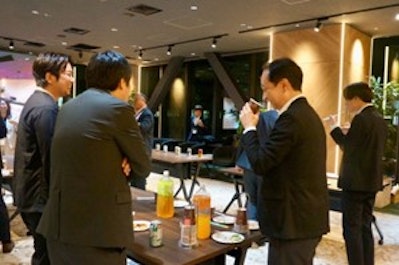 飲み物を飲みながら参加者が笑顔で歓談する写真