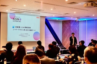「会議室.COM 情報交換会 ユーザーアクセス、問い合わせ傾向データ」と書かれたスライドを投影しながら司会が説明を進める写真