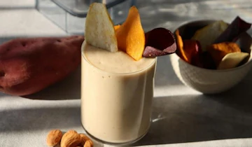 グラスに入ったさつまいもスムージーに野菜チップスをのせて。横にさつまいもとアーモンド