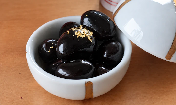 金粉をのせた黒豆を、白い蓋つきの小鉢に盛ったお正月の一品