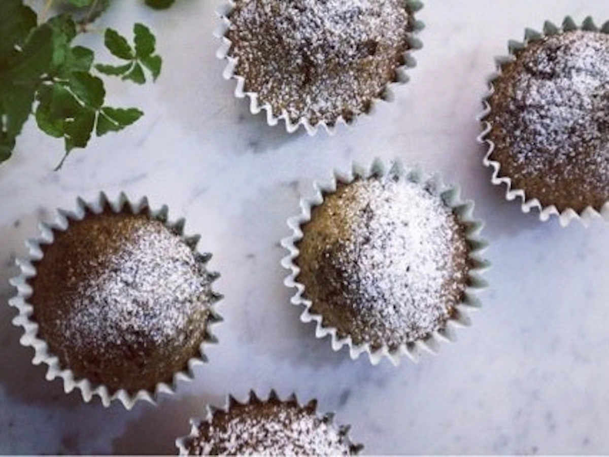 紙のカップに入った、粉砂糖をふったブルーベリーとチョコのマフィン