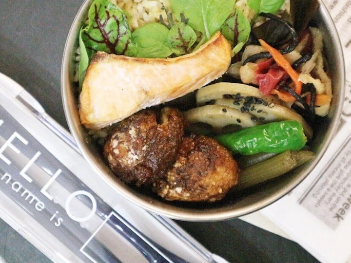 お弁当箱に詰めた、甘辛だれをからめた里芋の団子揚げと、玄米ごはん、焼き鮭、れんこんのきんぴら