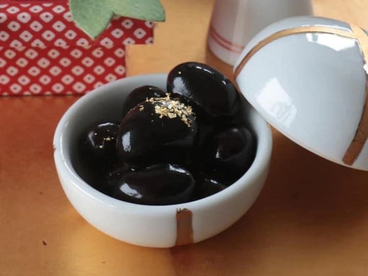 金粉をのせた黒豆を、白い蓋つきの小鉢に盛ったお正月の一品