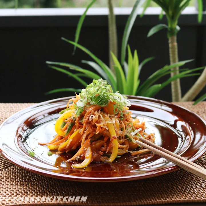 赤茶色の皿に盛り、ねぎをのせた千切り野菜と海藻麺の韓国風RAW焼きそば