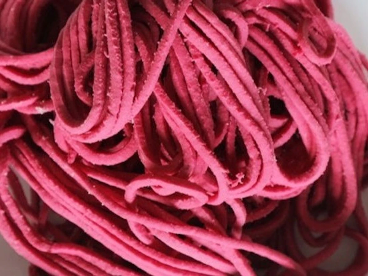 ビーツを練り込んだ、鮮やかなピンク色の細い手打ちパスタをふんわりと盛ったところ