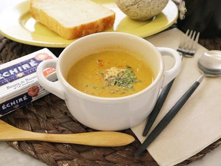 白いカップに入った、パセリを散らしたかぼちゃのポタージュ。黄色い皿に食パンを添えた朝ごはん