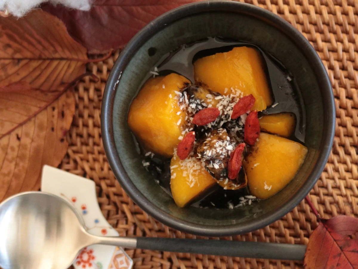 深い器に盛ったかぼちゃのいとこ煮。あずきとココナッツ、クコの実をのせて、紅葉の葉を添えて