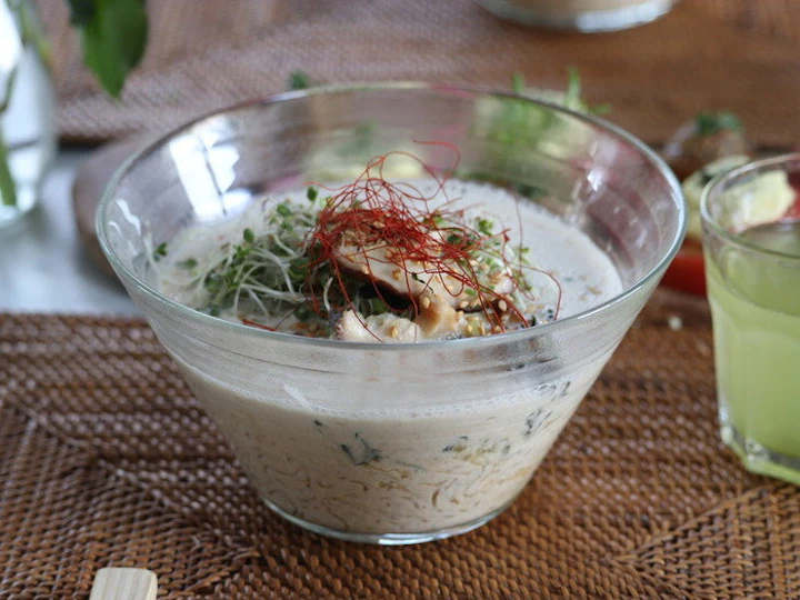 ガラスの器に盛ったRAWラーメン。白いクリーミーなスープに、しいたけ、スプラウト、糸唐辛子、ごまをトッピング