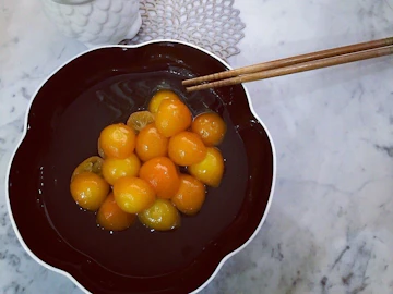 黒い花形の器に入った、つややかな金柑のみりん煮