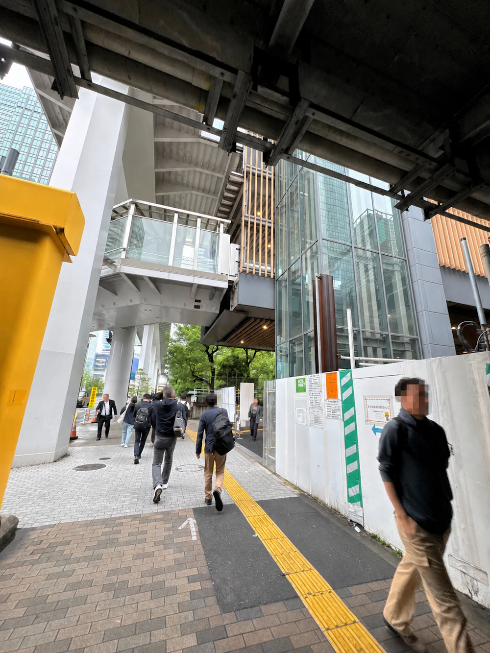 高架下を進むとガラス張りのエレベーター棟と歩行者デッキが見える