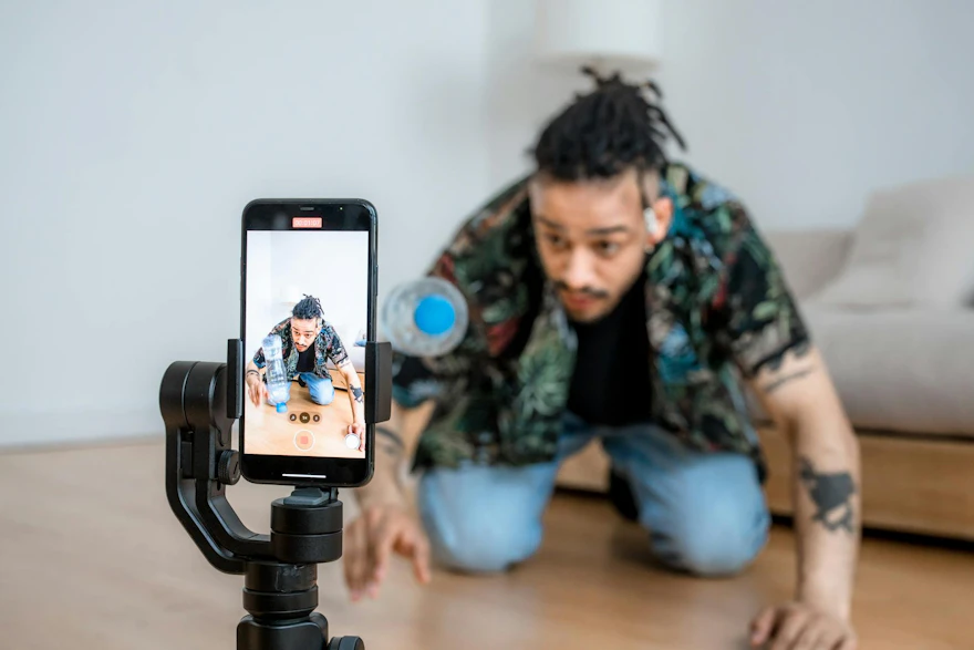 Man filming creative content with smartphone on gimbal indoors.