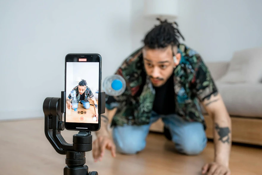 Man filming creative content with smartphone on gimbal indoors.