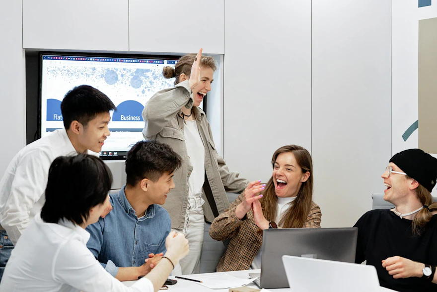 A diverse group of professionals celebrating a successful project in a modern office setting.