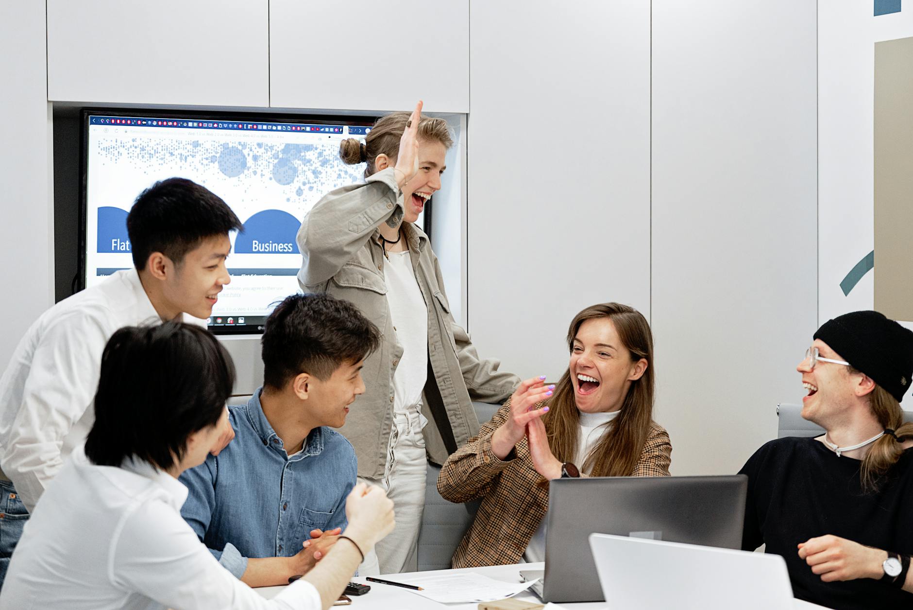 A diverse group of professionals celebrating a successful project in a modern office setting.