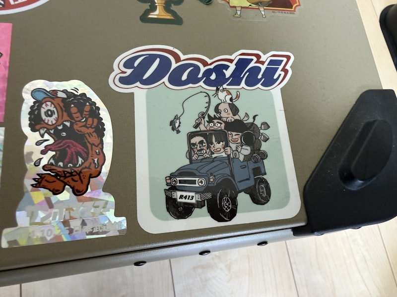 Doshiと書かれたロゴのステッカー。車のイラストが書かれている。