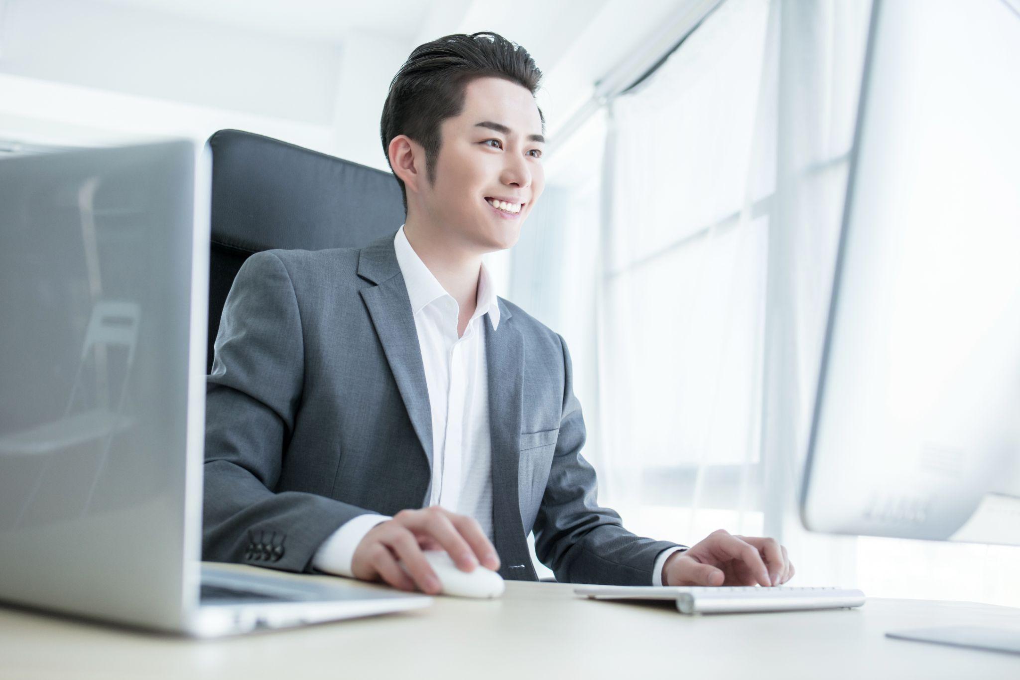 笑顔でパソコンを操作するビジネスパーソン