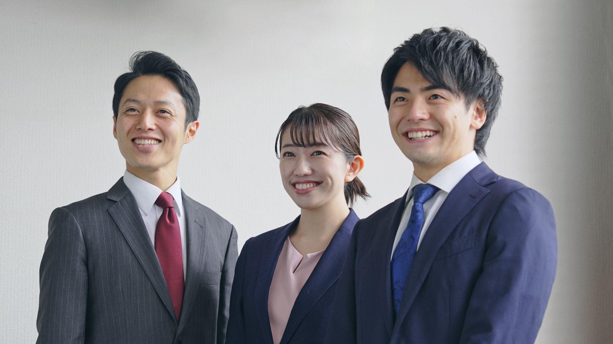 笑顔で並ぶビジネスパーソン3名