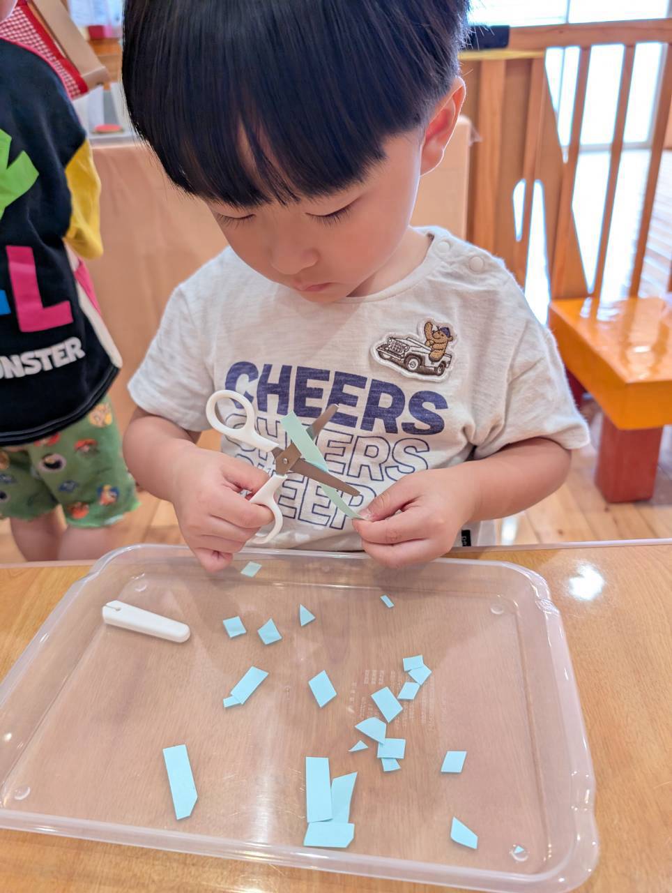 紙と刃先を見ながら切る位置を調整する子ども