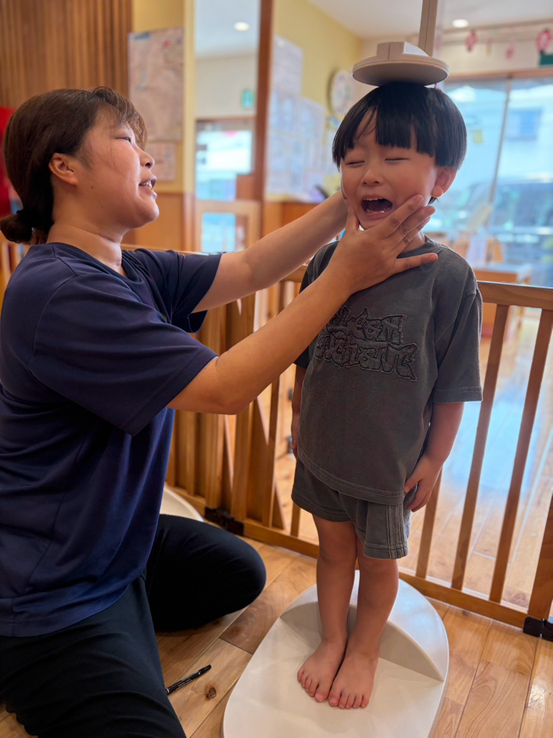 保育士に見守られながら身体測定を受ける子ども