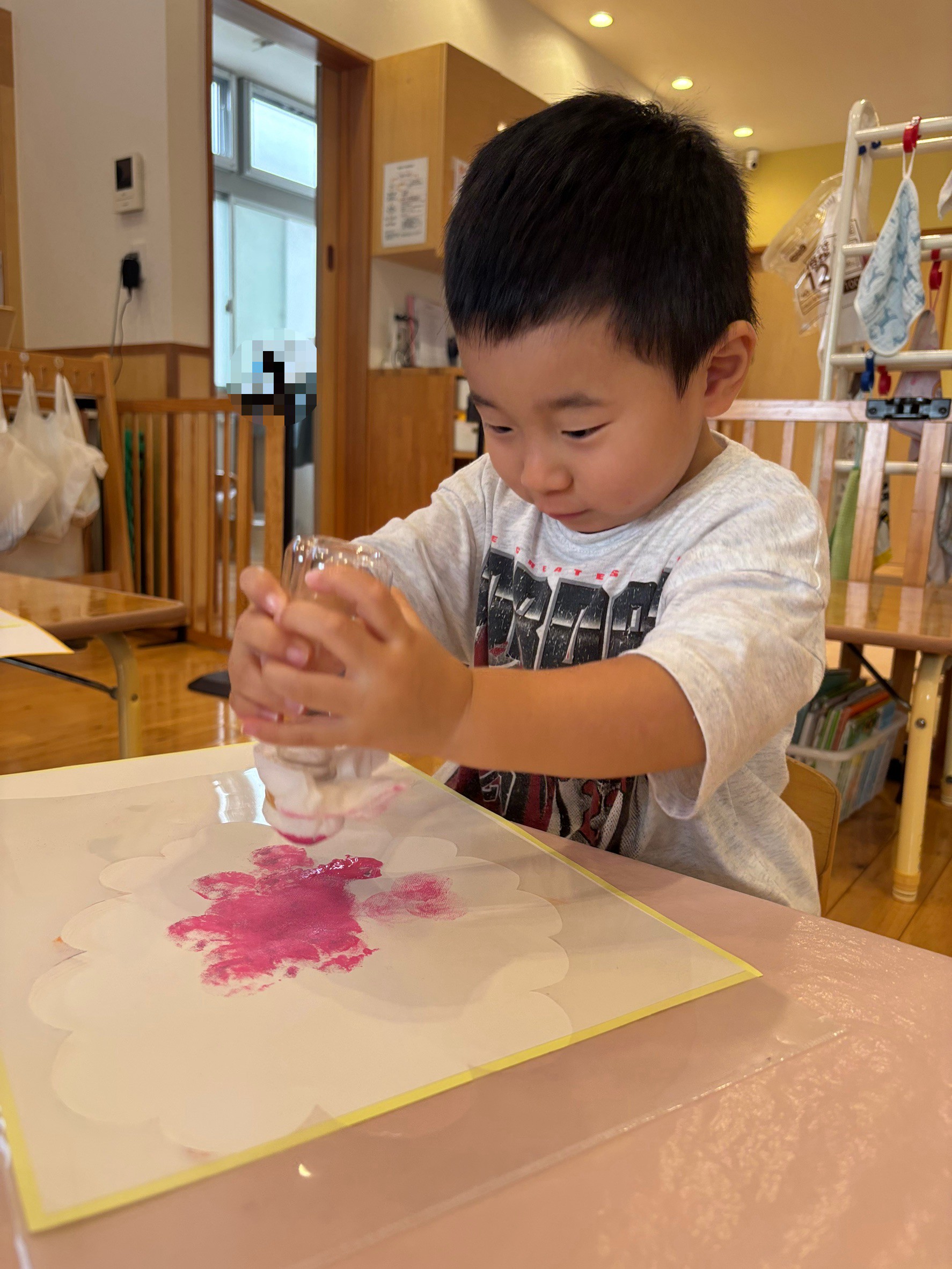 道具を両手で押して紙に模様をつける子ども