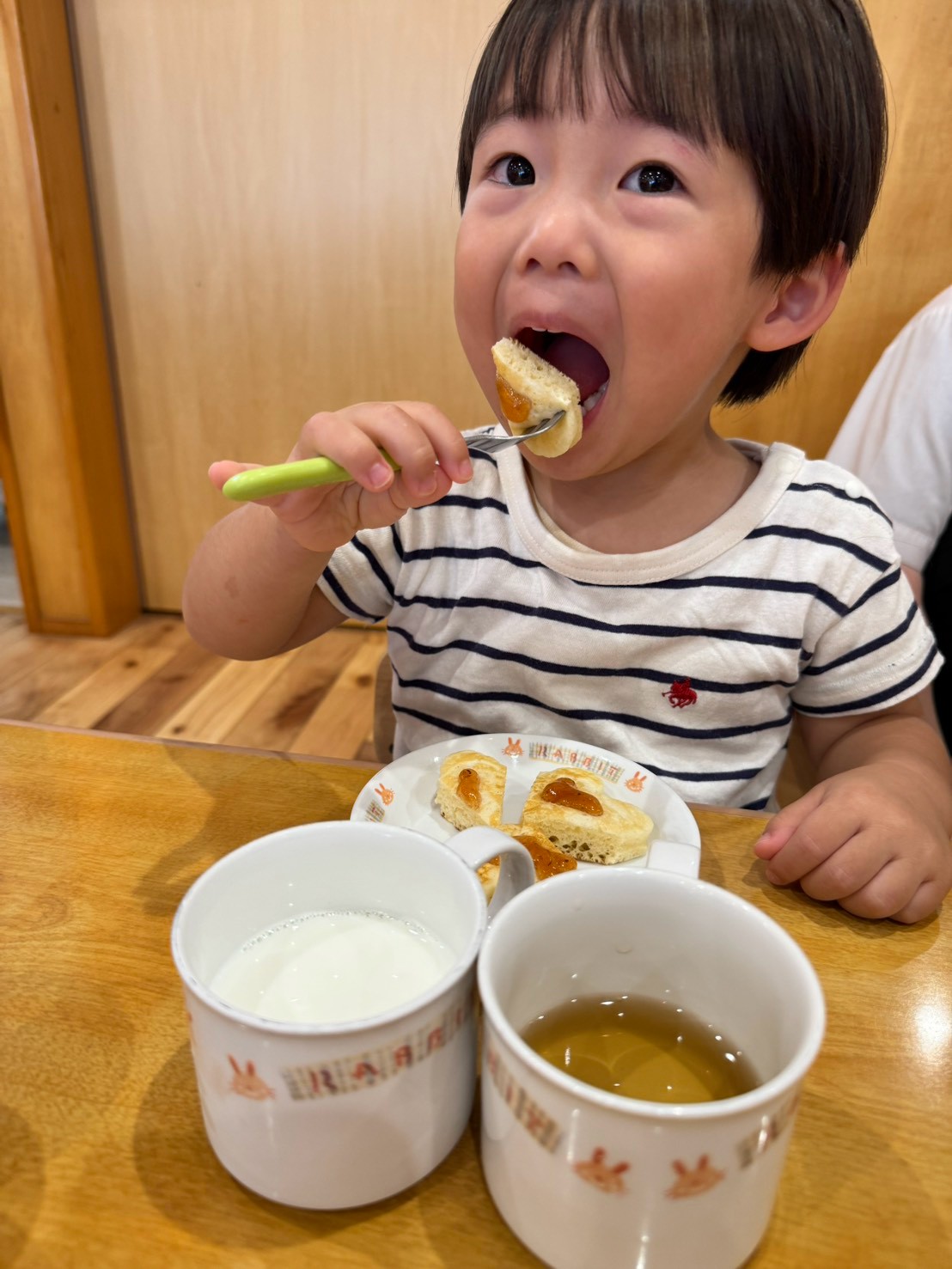 フォークでハート形のおやつを口へ運ぶ子ども