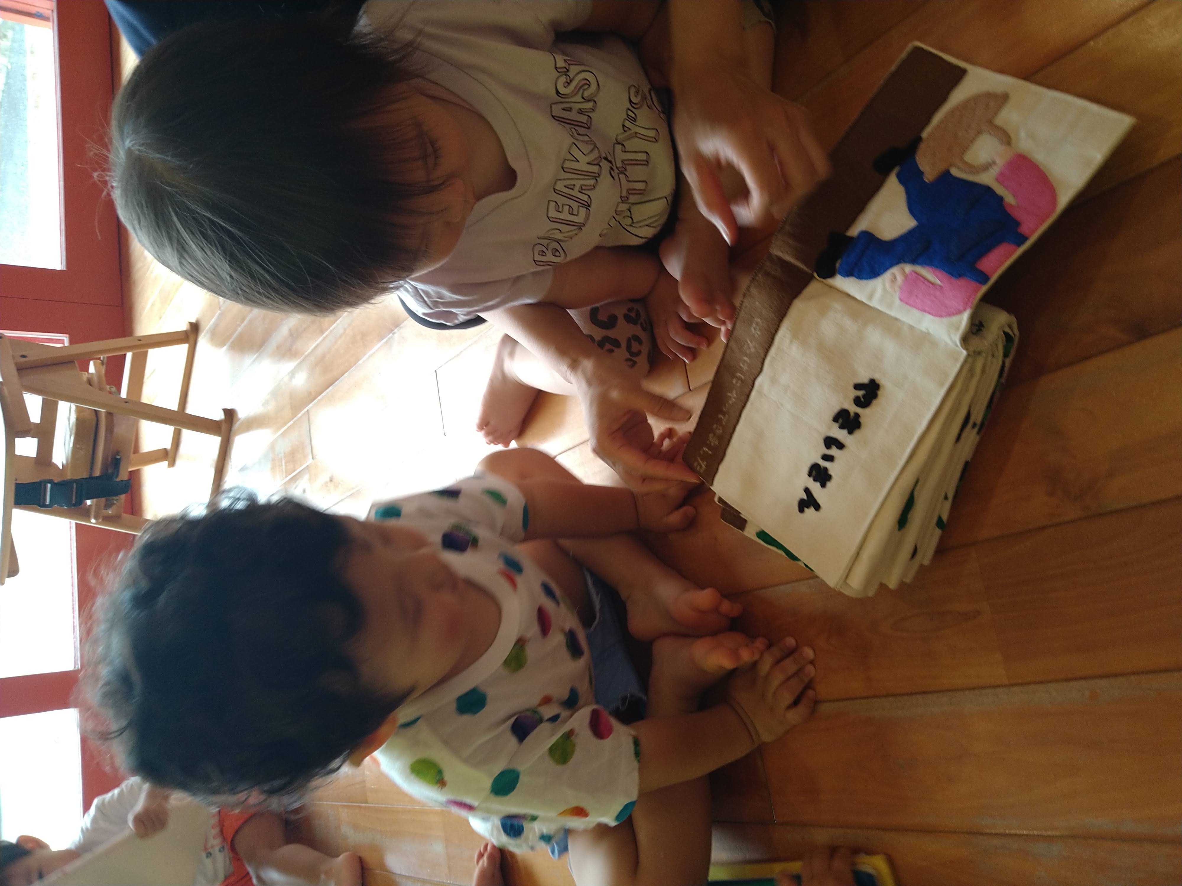 友だちと布絵本の同じページへ指を伸ばす子どもたち