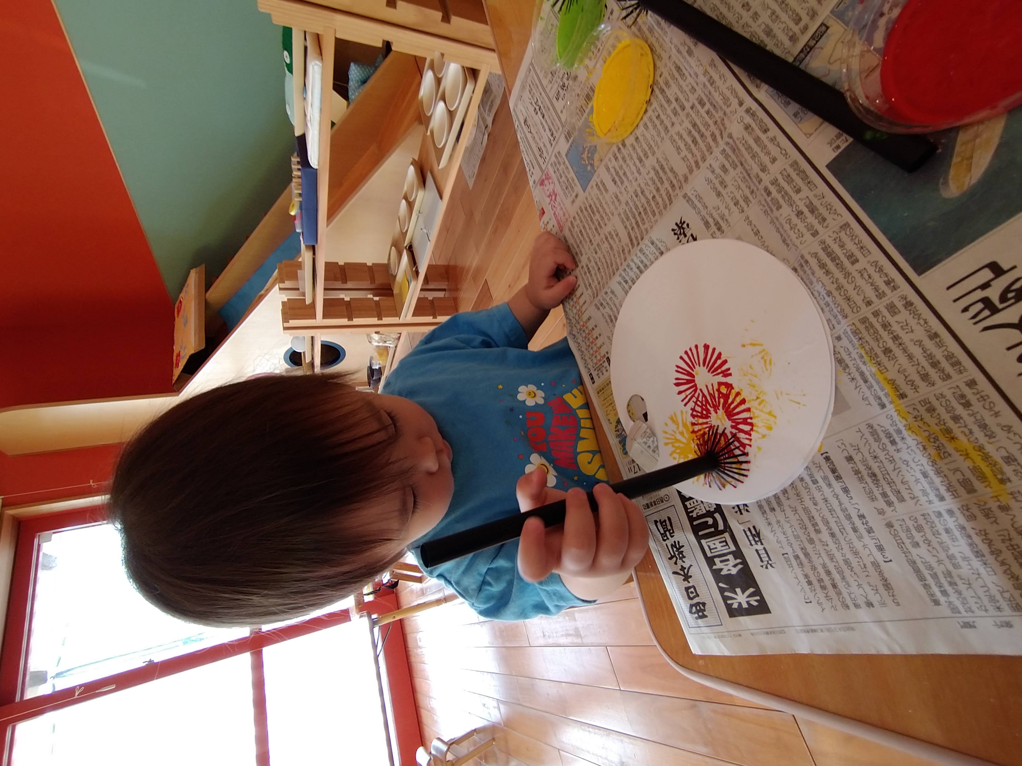 赤と黄色のストロースタンプを重ねる子ども
